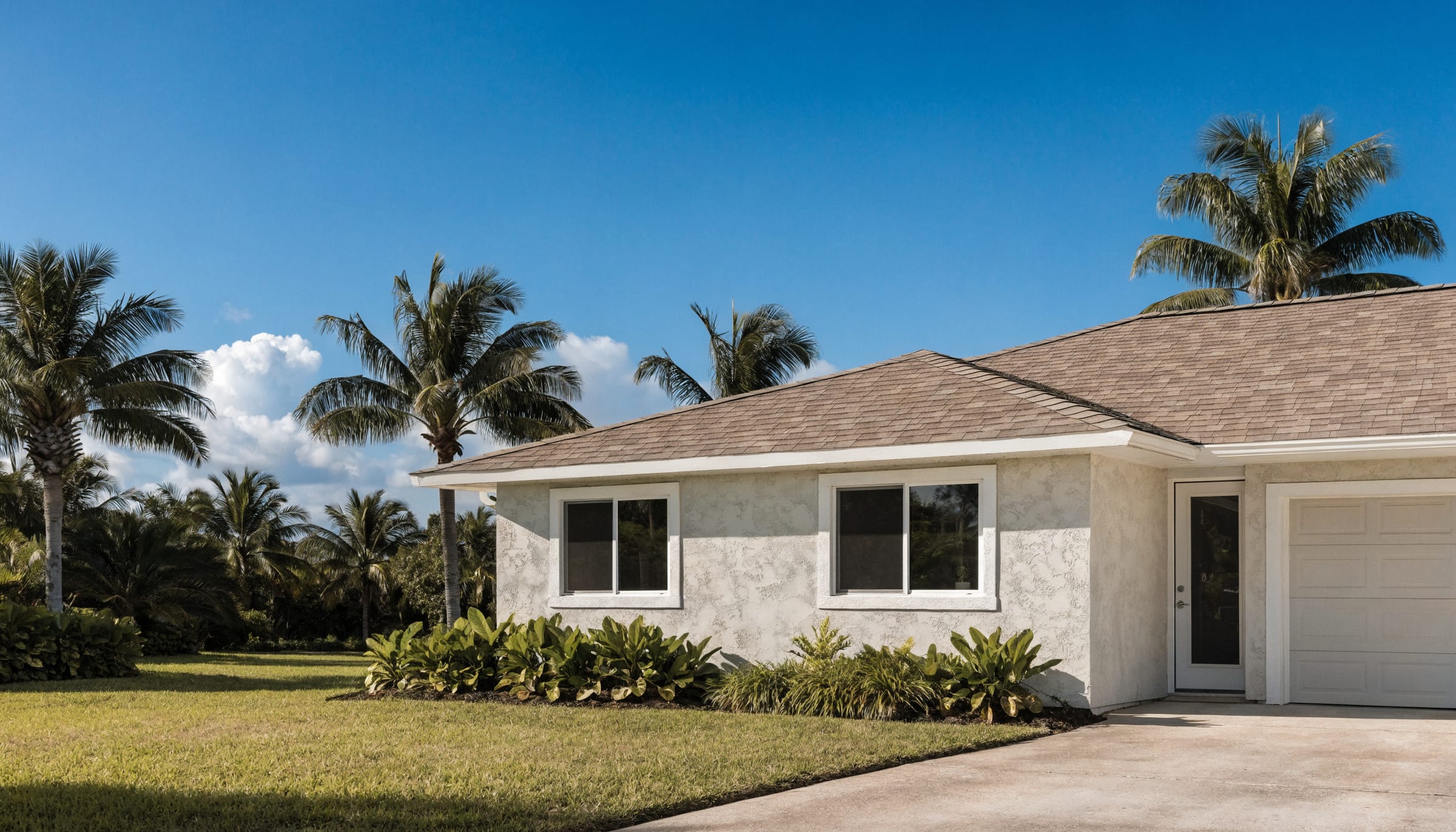 A single-story Florida home with white impact windows, a white entry door, a wind-rated garage door and a shingle roof