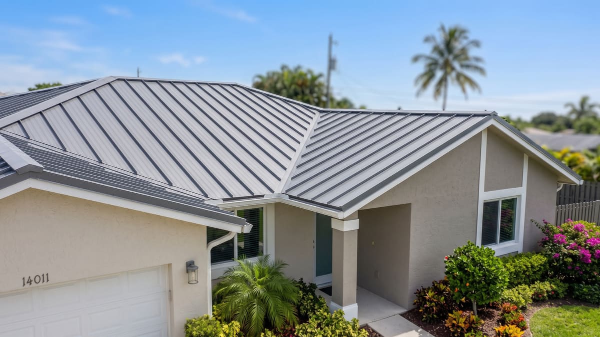 Grey standing-seam metal roof on a single-story Florida home with palms