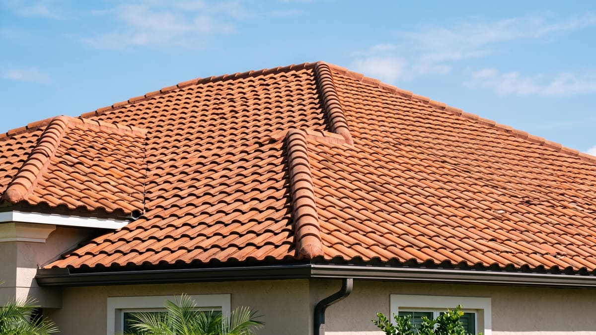 Terracotta barrel tile roof on a stucco Florida home under a clear sky