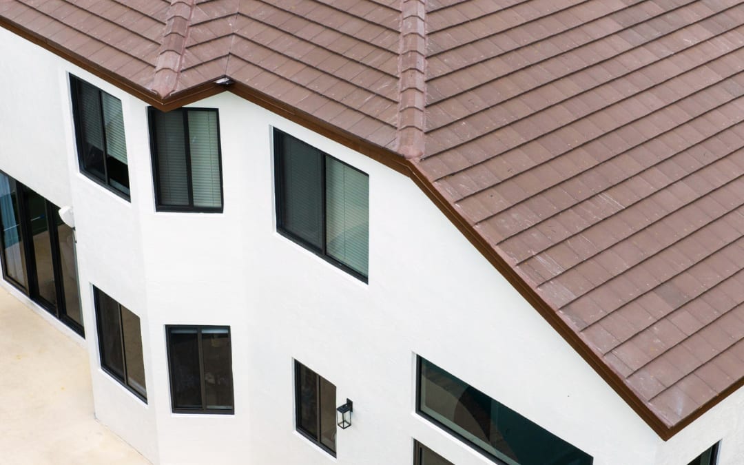 Aerial view of a two-story Lake Worth home with a new brown concrete tile roof, dark-framed impact windows and sliding doors, and freshly painted white stucco