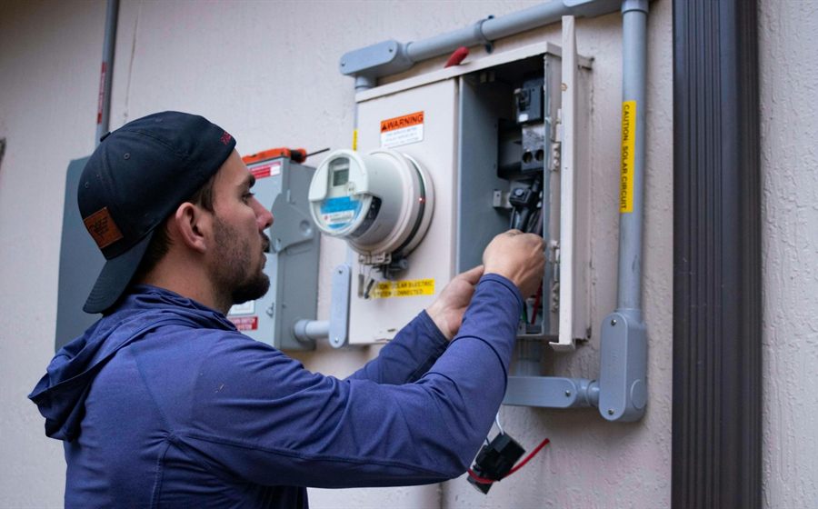 Technician servicing the electrical service panel on a stucco home
